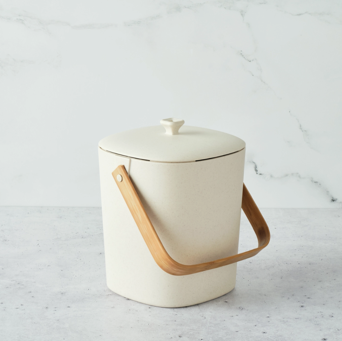 White compost bin with a wooden handle on a light gray background