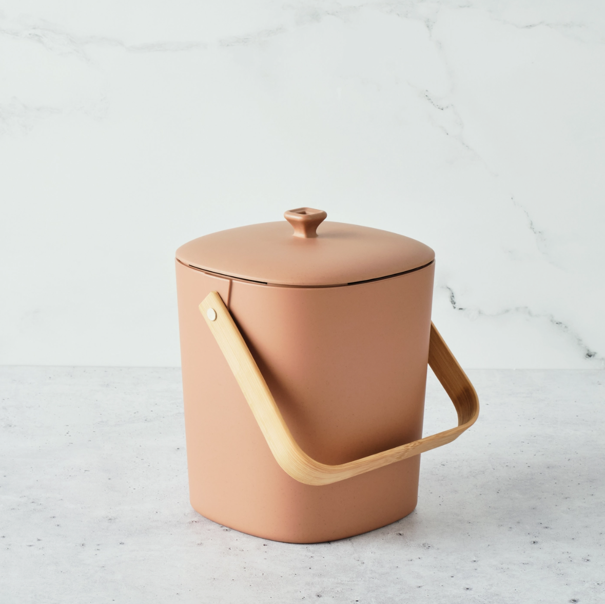 Terracotta compost bin with wooden handle on a light gray background
