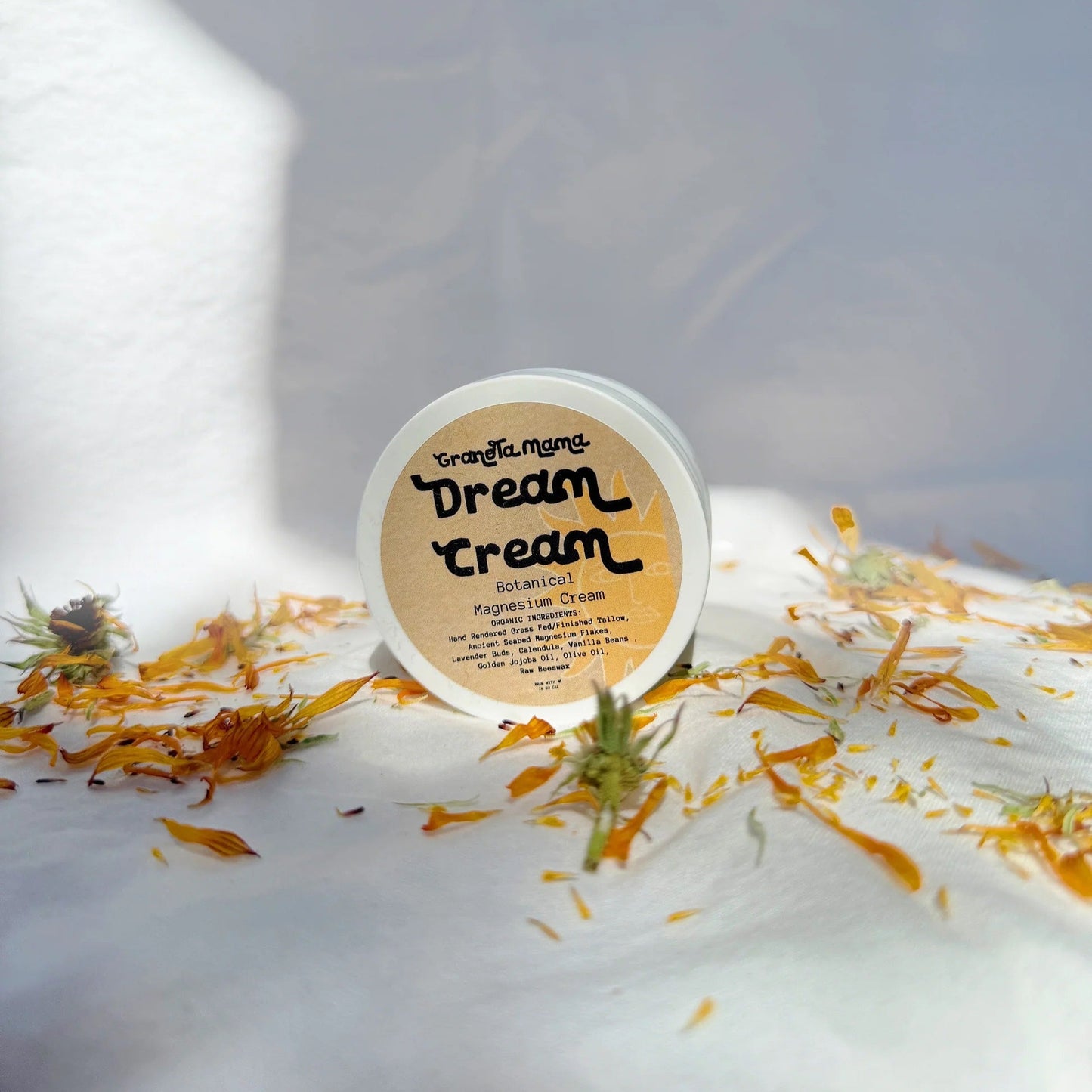 Container of Dream Cream with flowers on a white surface