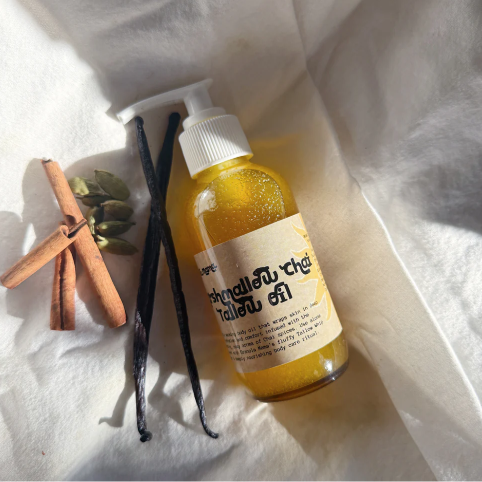 Clear bottle with yellow body oil with a label on a white fabric background