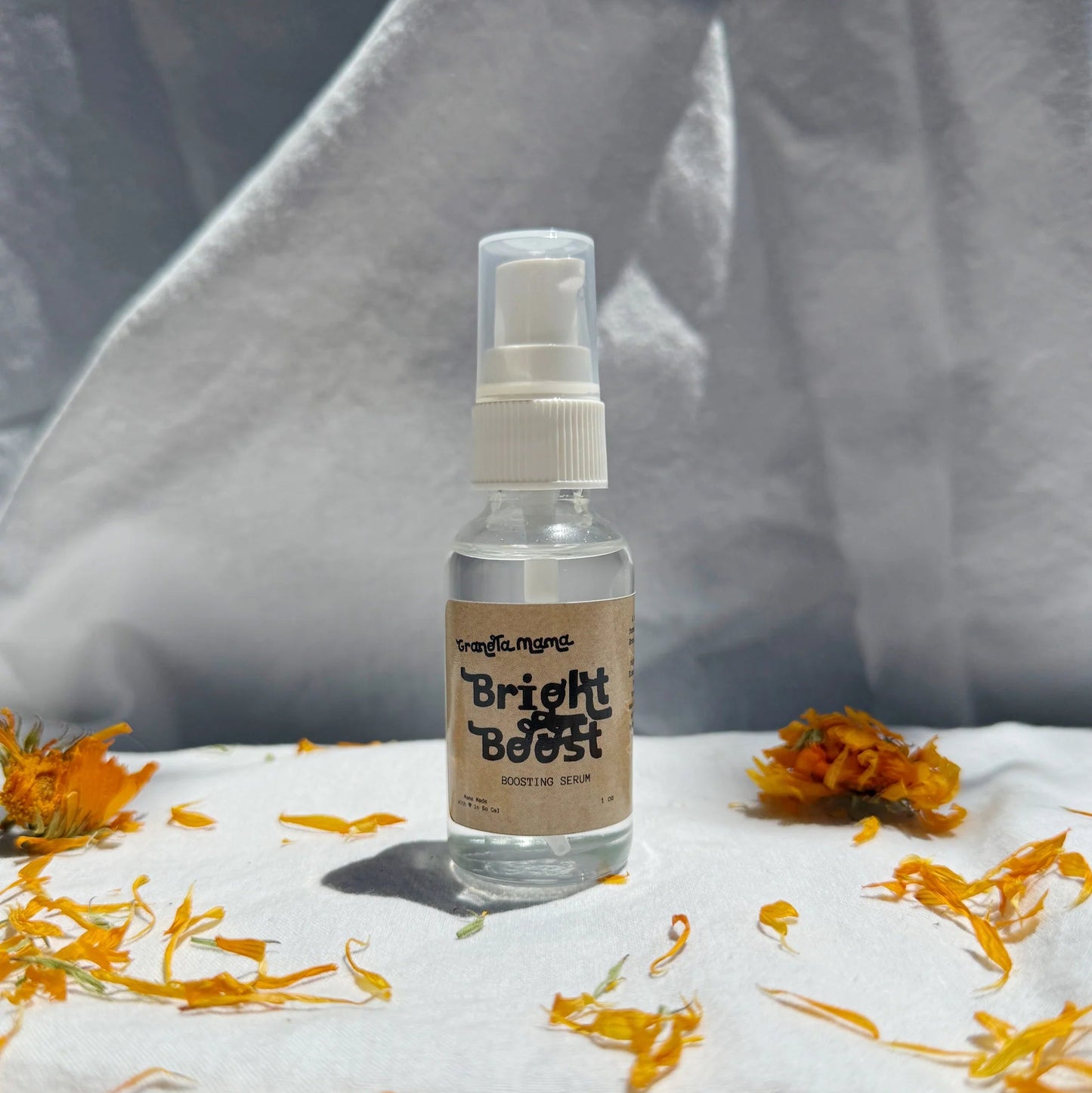 Clear spray bottle labeled 'Bright Boost' on a white surface with yellow flowers.