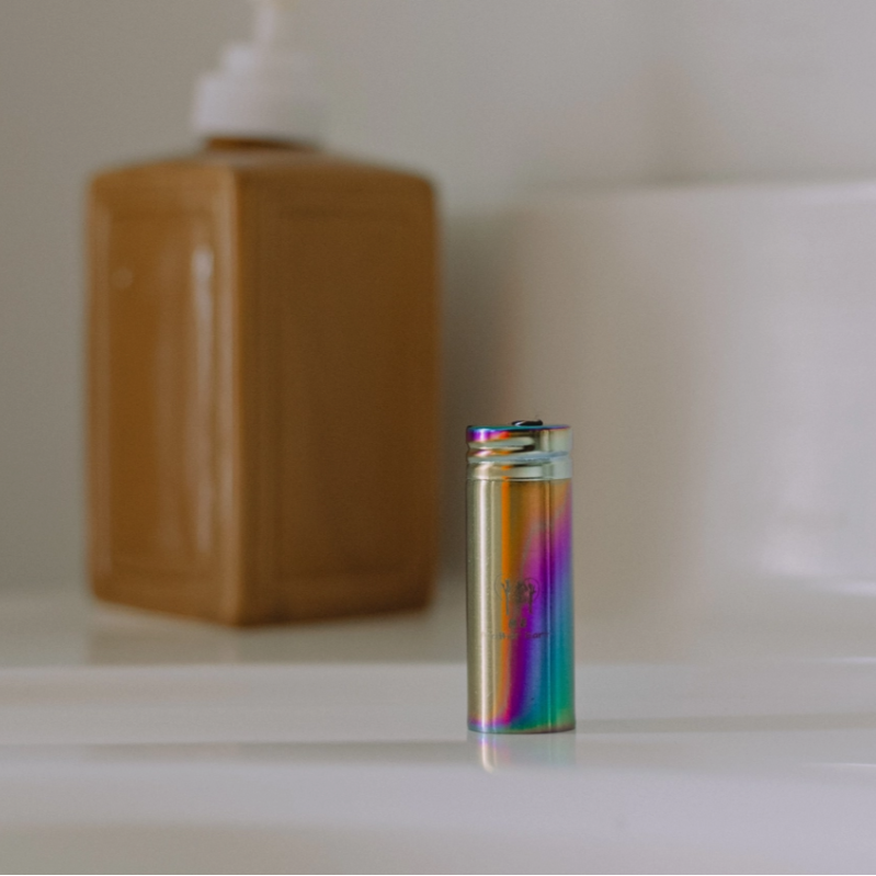 Multicolored floss holder on a bathroom counter with soap dispenser and sink in the background