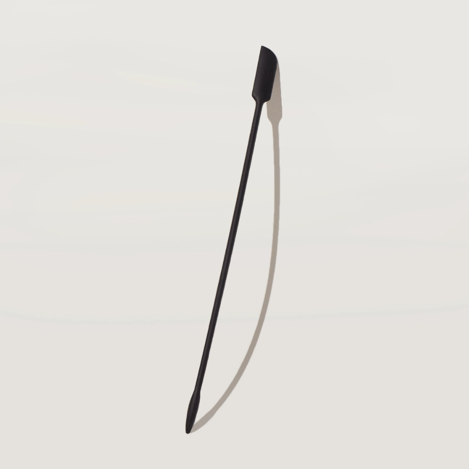 Black thin long spatula on a light gray background