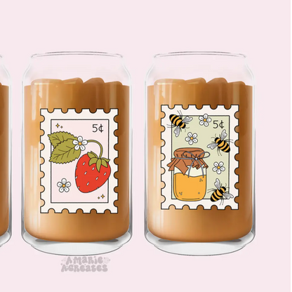 Two glass jars with decorative labels featuring a strawberry and a honey jar on a pink background.