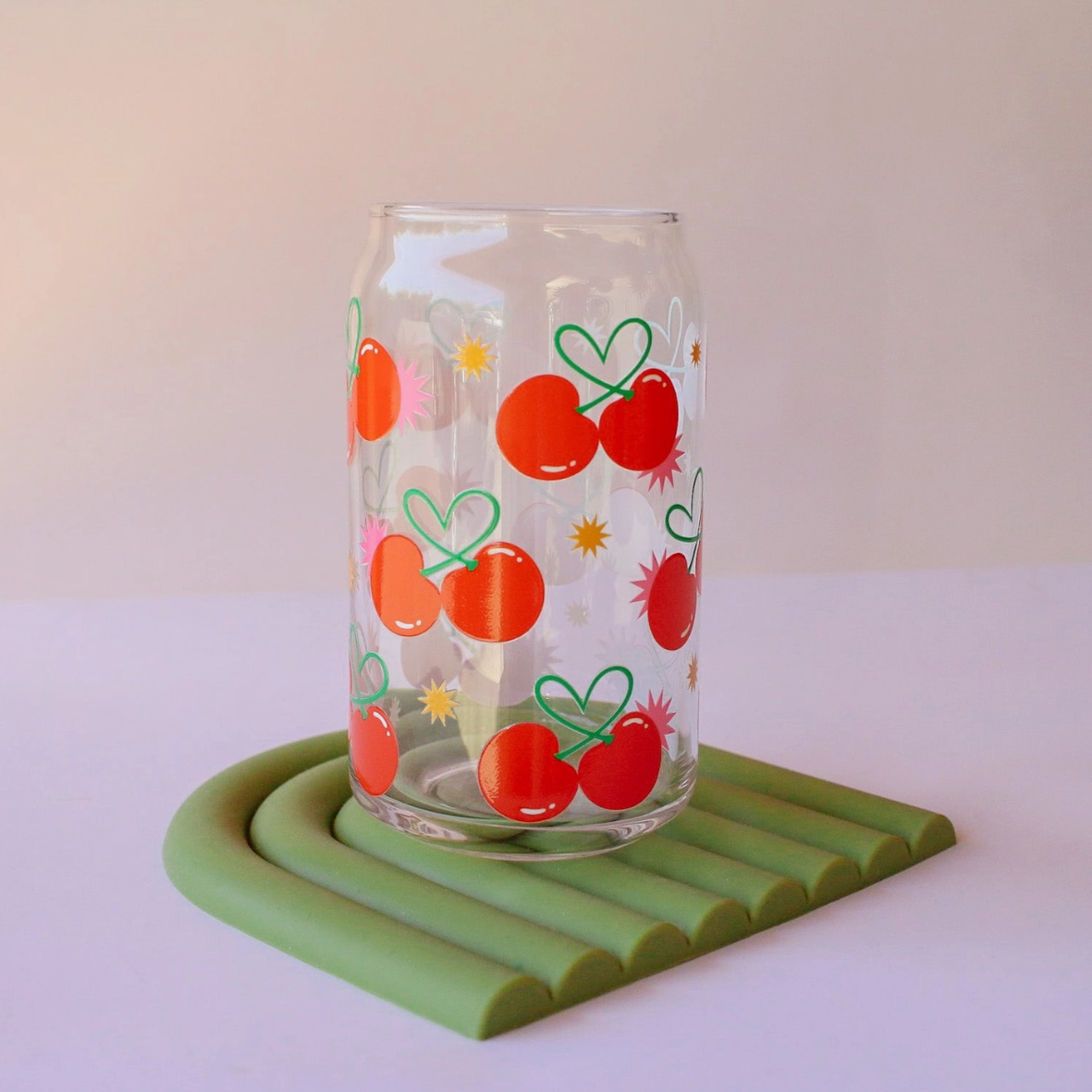 Clear glass with cherry design on a green coaster