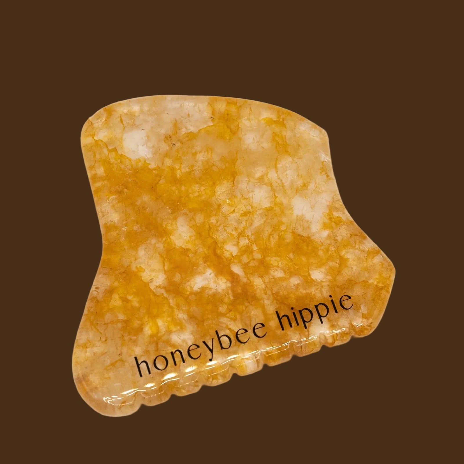 Yellow gua sha stone with 'honeybee hippie' text on a beige background