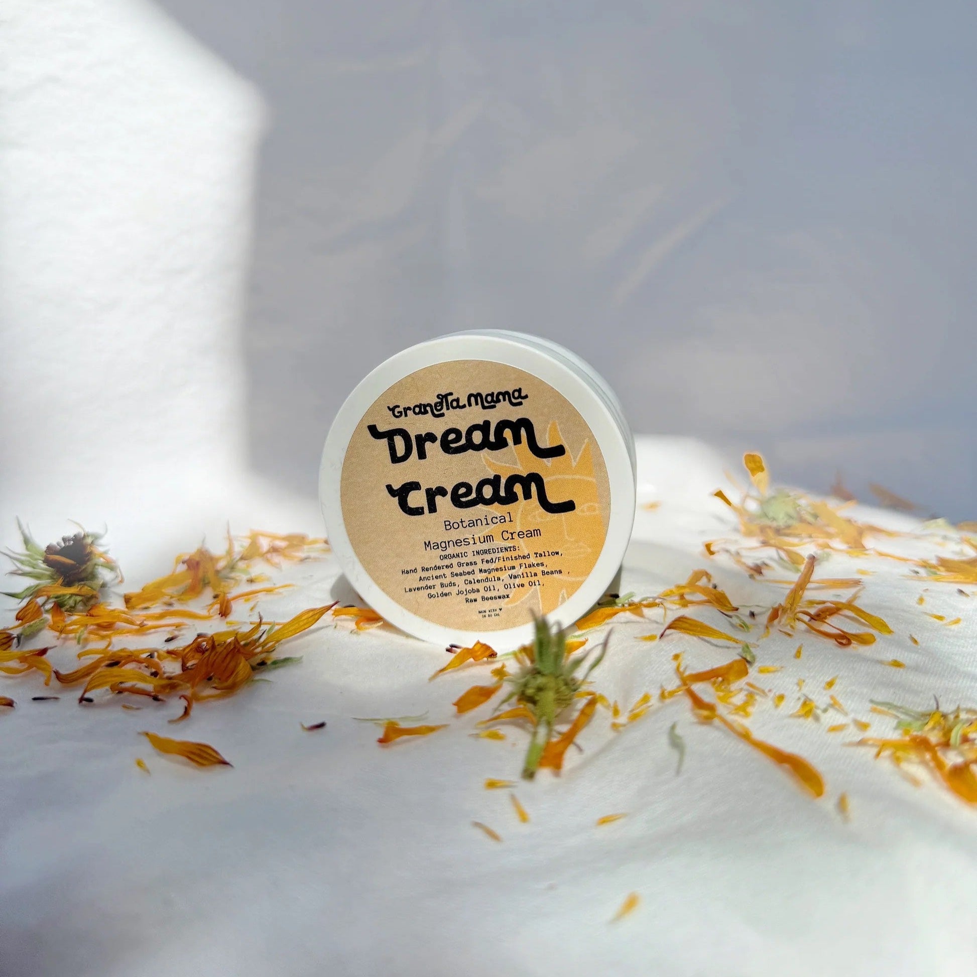 Container of Dream Cream with flowers on a white surface
