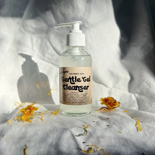 Bottle of 'Gentle Gel Cleanser' on a textured surface with flowers