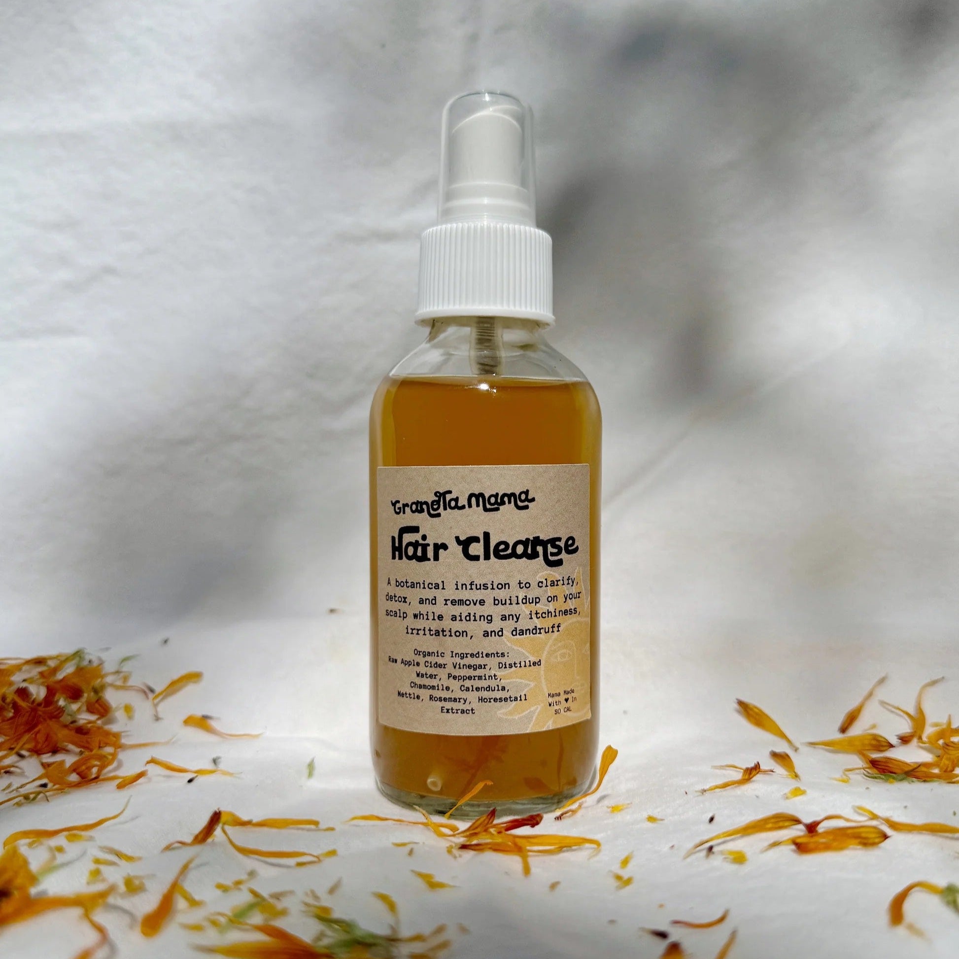 Bottle of hair cleanse with calendula flowers on a white background