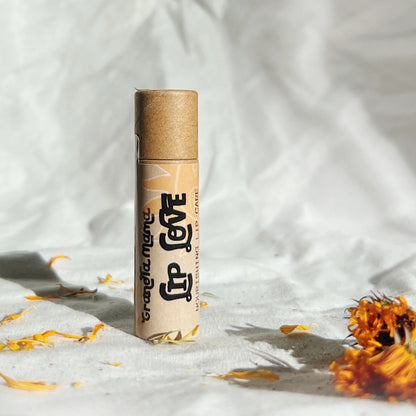 Paper lip balm container with a label on a textured white background