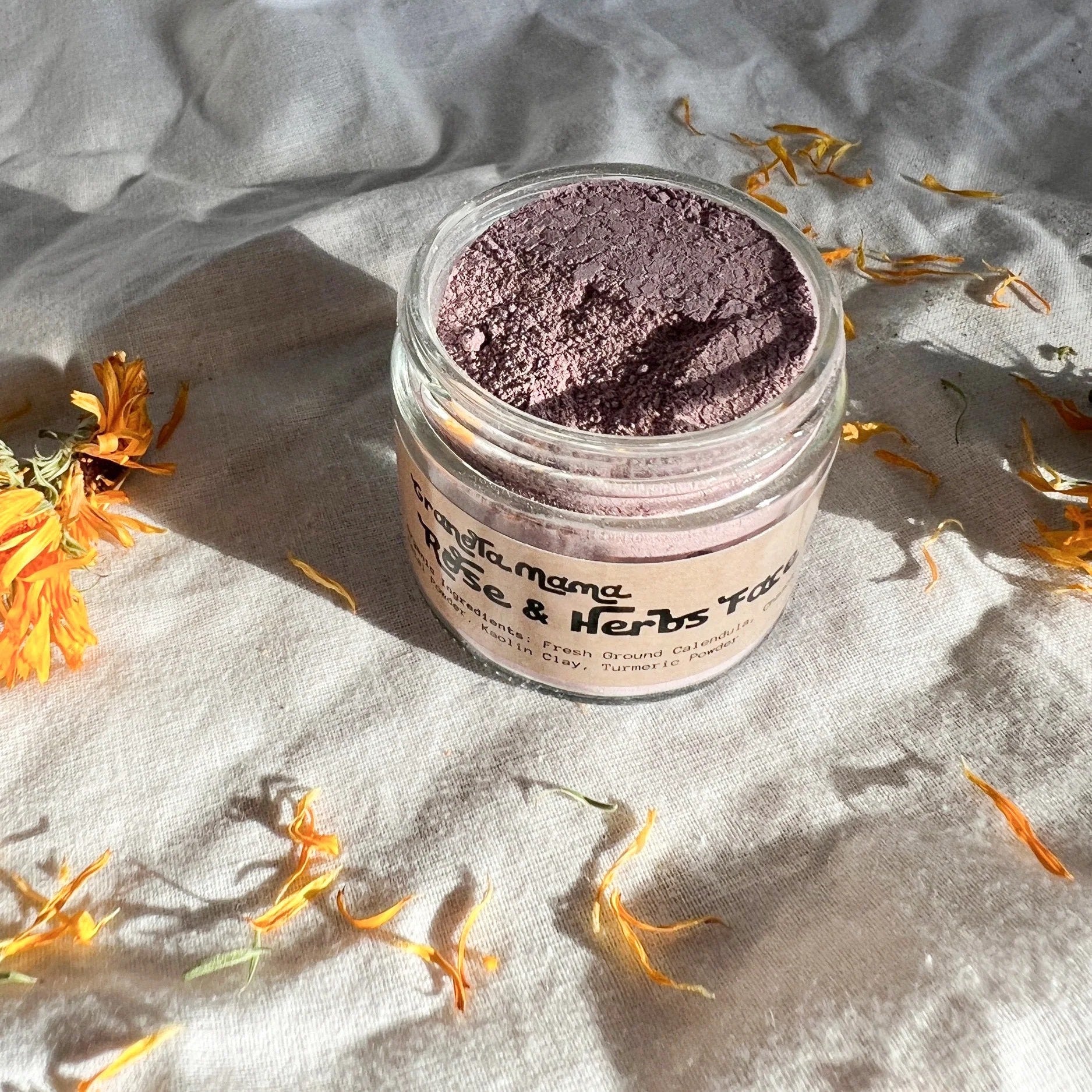 Jar of pink face powder with dried flowers on a textured surface