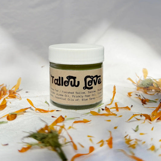 Jar of 'Tallow Love' product on a textured white background with calendula flowers.