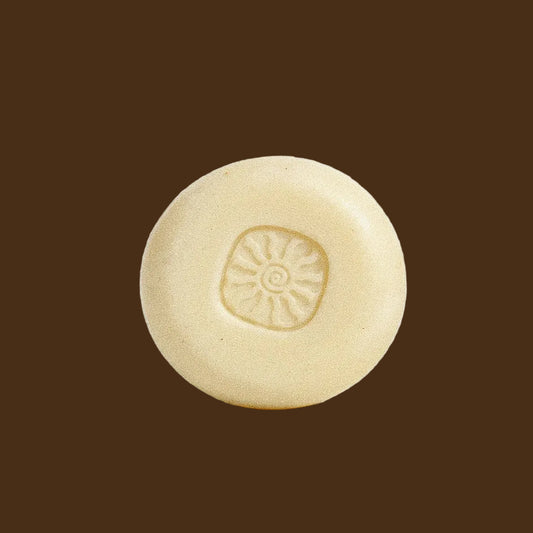 A single round, pale cream-colored soap bar with a sunburst pattern embossed in the center, photographed on a clean white background.