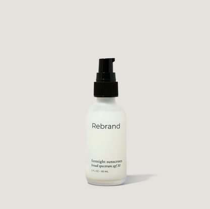Sunscreen bottle labeled 'Rebrand' on a light gray background