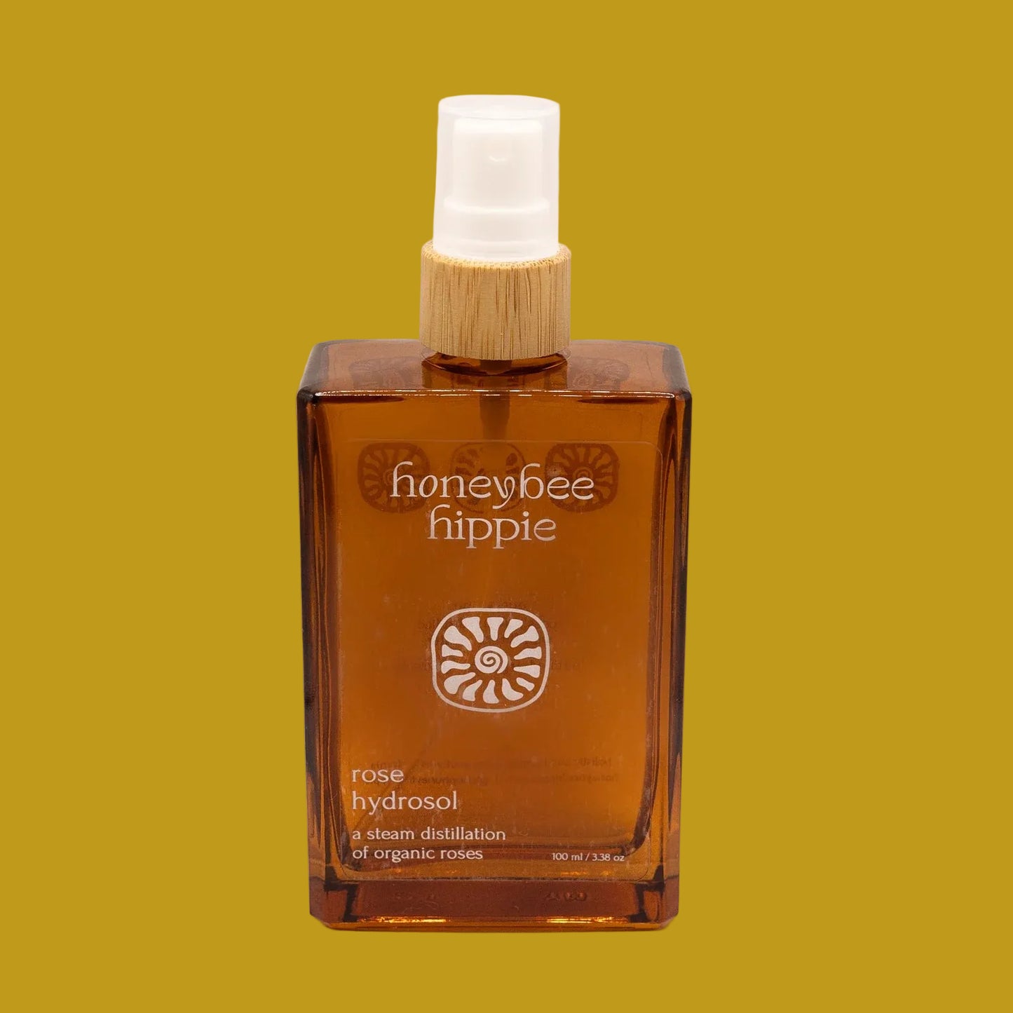 Honeybee Hippie rose hydrosol bottle on a beige background