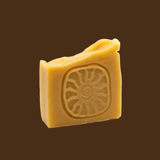 Bar of yellow soap with a sun design on a beige background